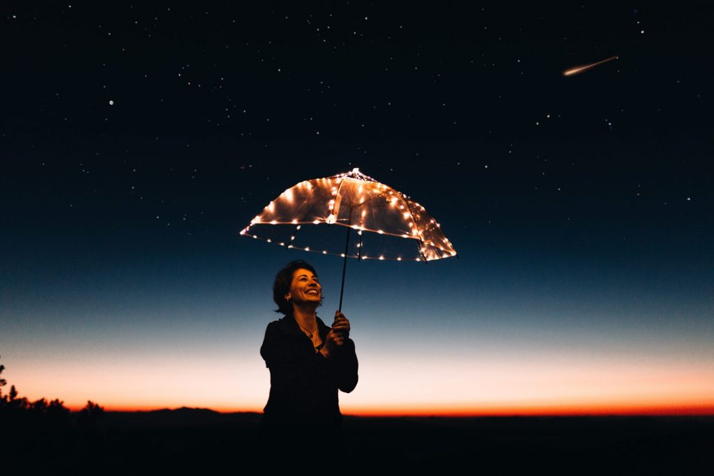 Woman holding umbrella under stars at night