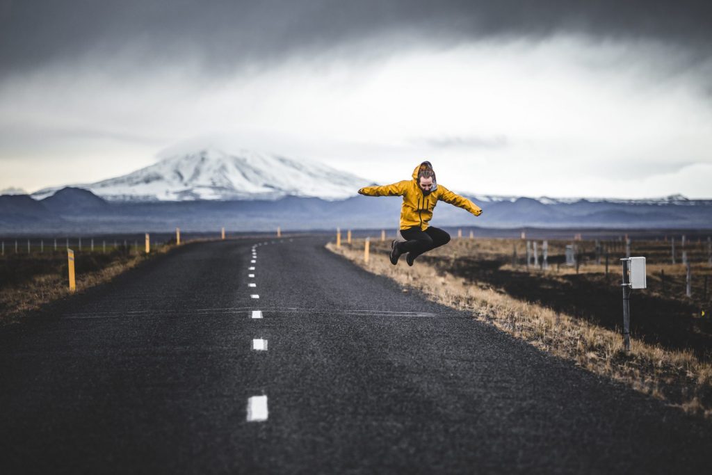 Woman jumping on road with mountain the background