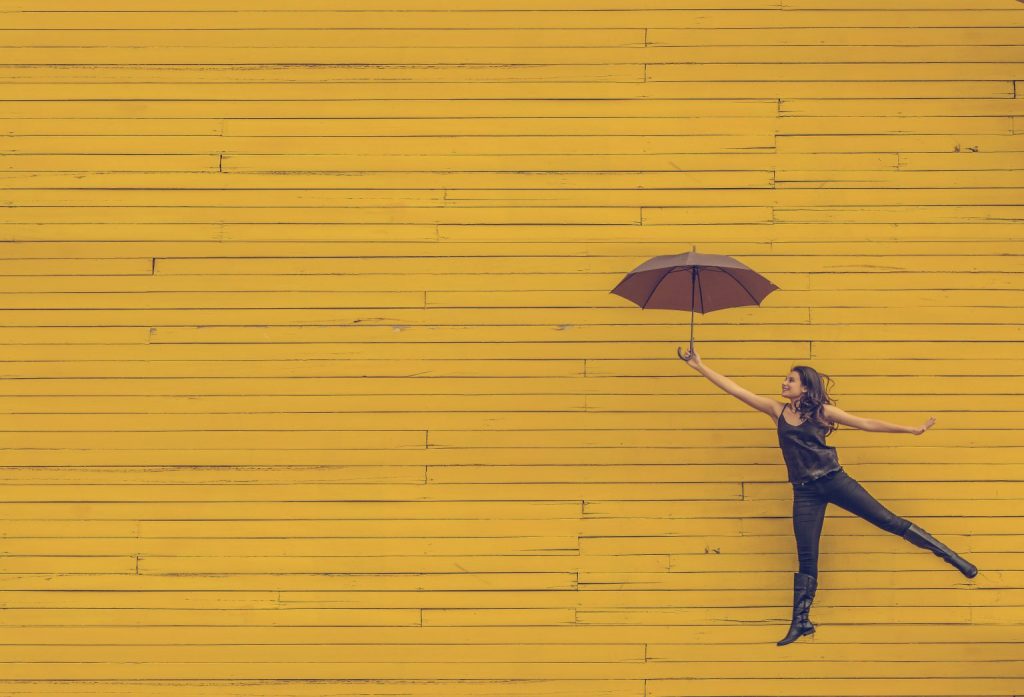 Woman in front of yellow background holding umbrella
