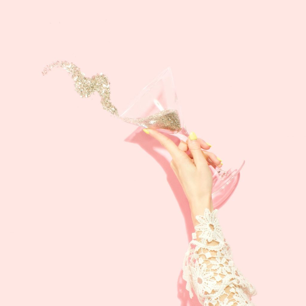 Hand holding wine glass with glitter